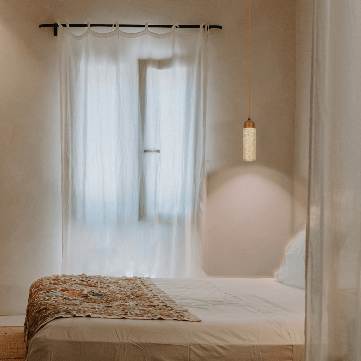 Vue en situation du luminaire éclairé au-dessus d'un lit à couverture fleurie
