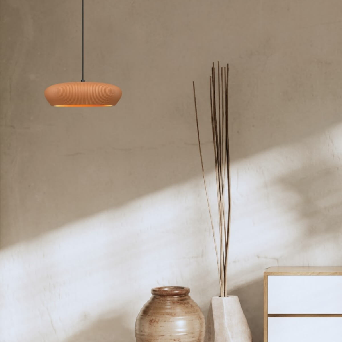 Scène de vie montrant le luminaire suspendu, vase, branches et meuble en bois