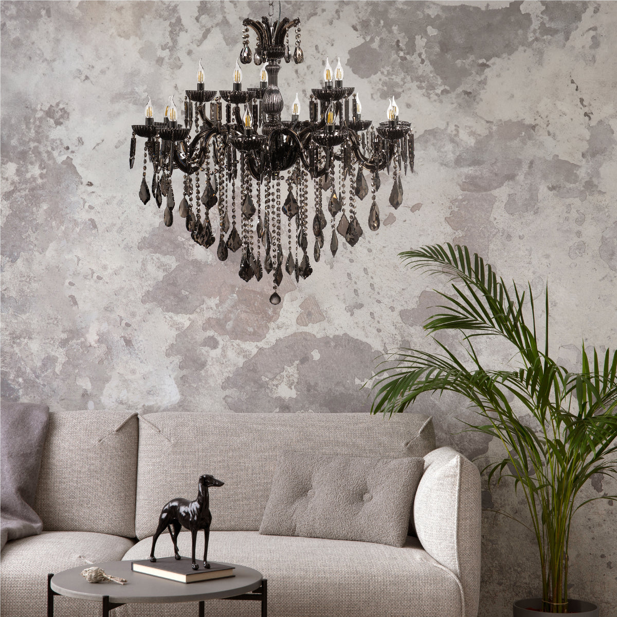 Lustre suspendu dans un salon gris avec canapé et plante.