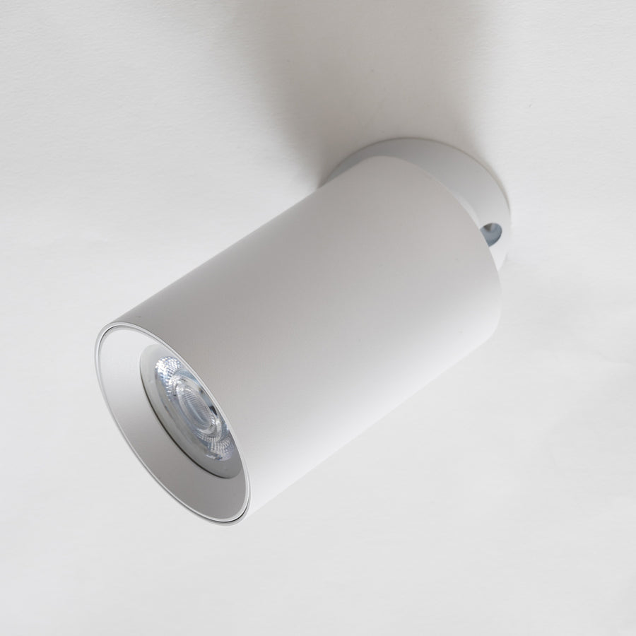 Spot blanc incliné sur plafond blanc, tête orientable éclairant en biais