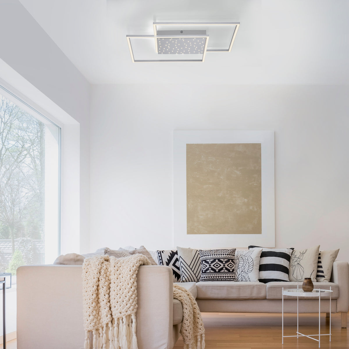 Luminaire fixé au plafond dans un salon blanc aux coussins graphiques