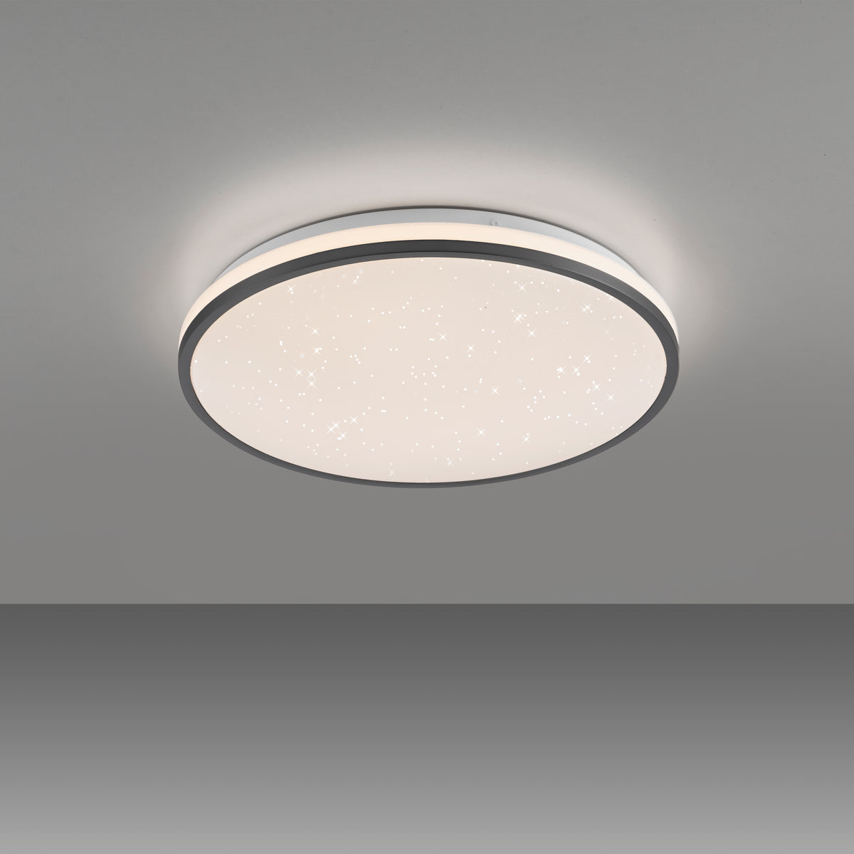 Plafonnier allumé fixé au plafond gris, halo lumineux diffus tout autour