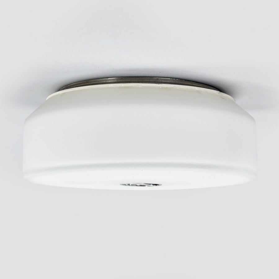 Profil latéral du plafonnier blanc fixé au plafond, montrant sa forme cylindrique et son cerclage.