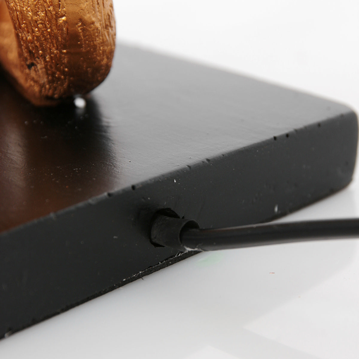 Détail du socle noir montrant la sortie du câble d'alimentation