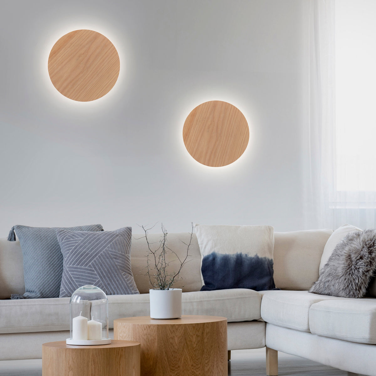Mise en ambiance dans un salon avec deux appliques murales rondes en bois allumées.