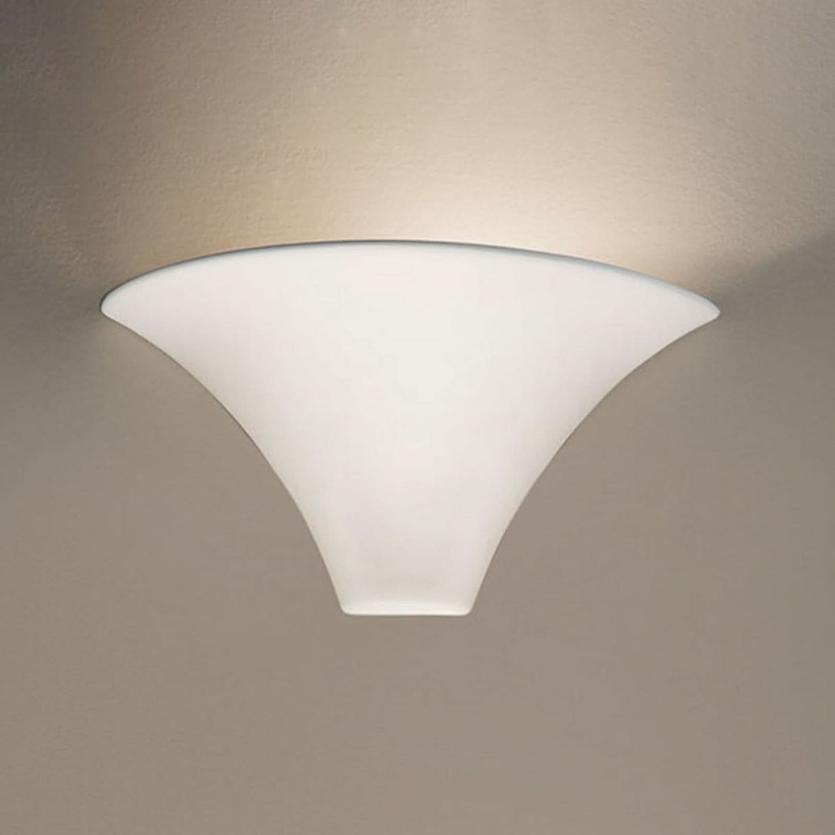 Applique murale blanche allumée, diffusant une lumière chaude sur un mur beige.