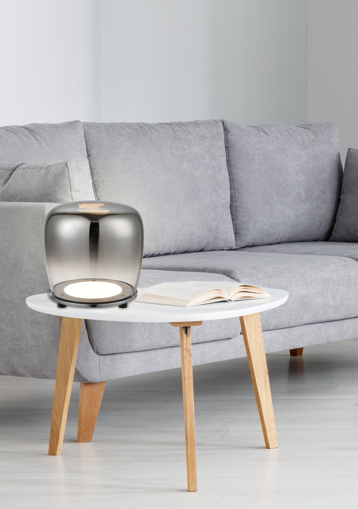Mise en ambiance de la lampe posée sur table basse devant un canapé gris