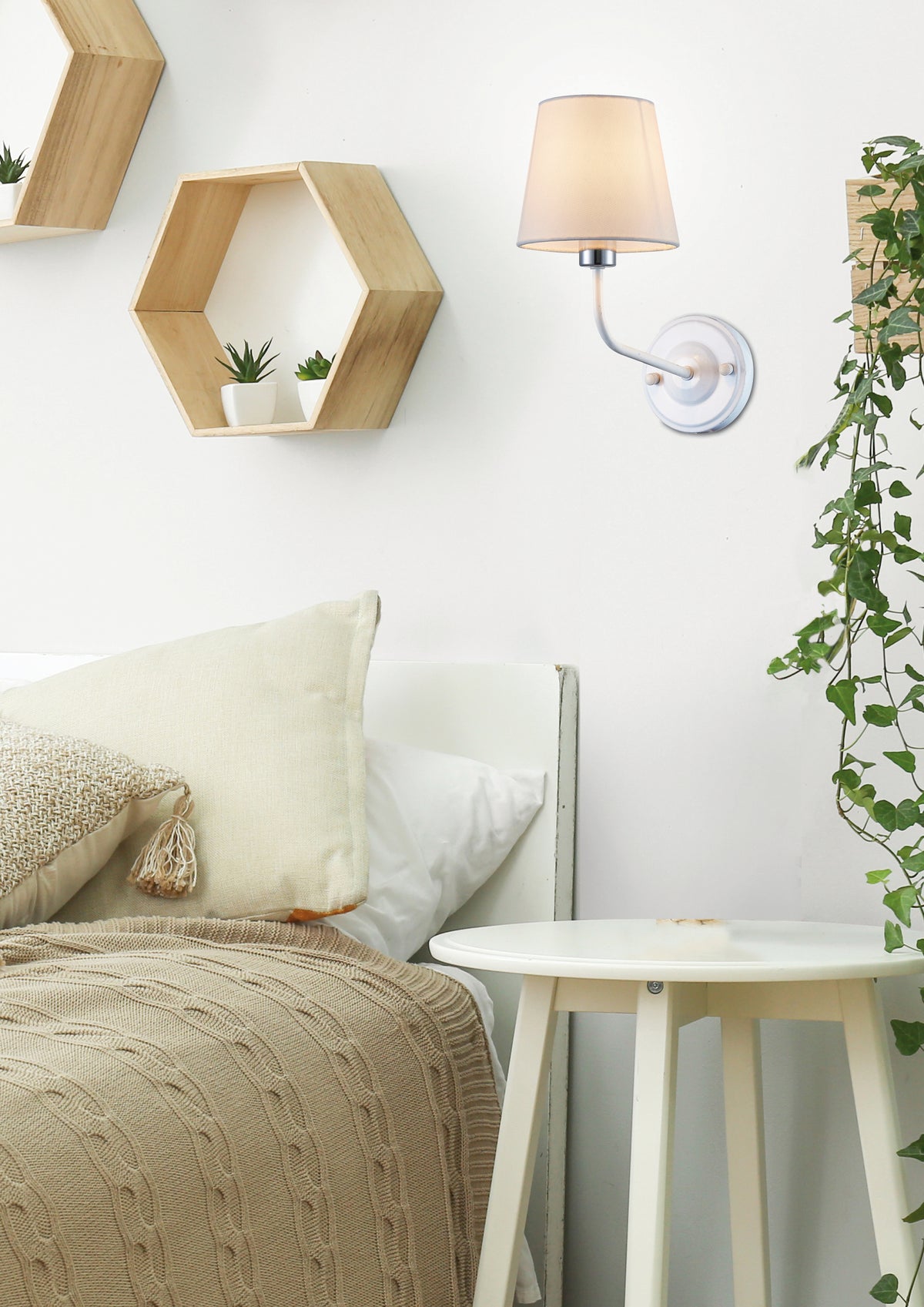 Vue rapprochée de l'applique fixée au mur blanc, au-dessus d'une table de chevet.