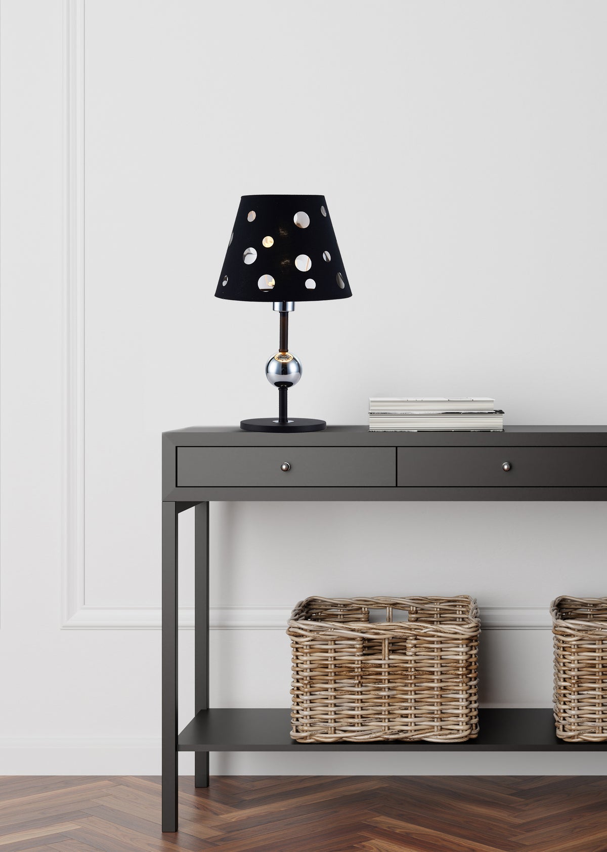 Mise en ambiance de la lampe posée sur une console grise devant un mur blanc