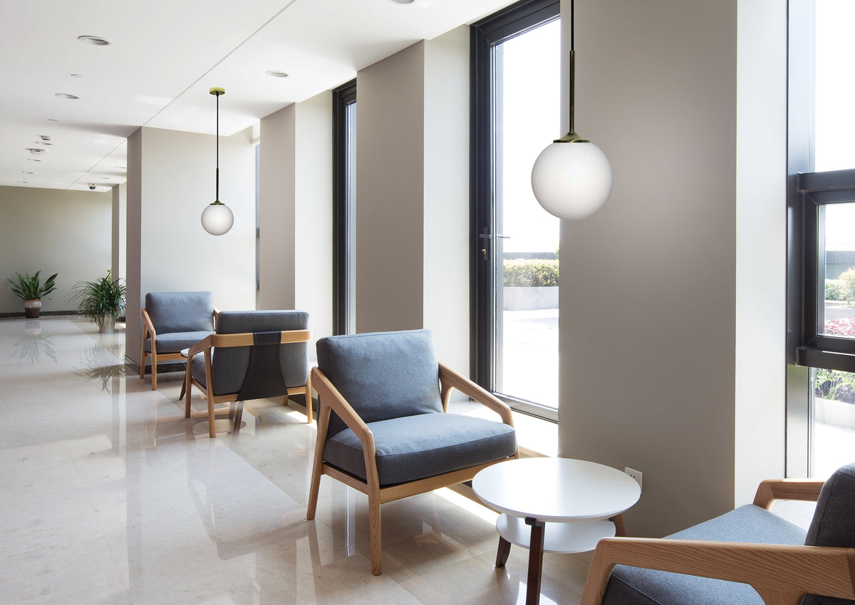 Mise en ambiance du couloir lumineux avec deux suspensions globes et fauteuils gris