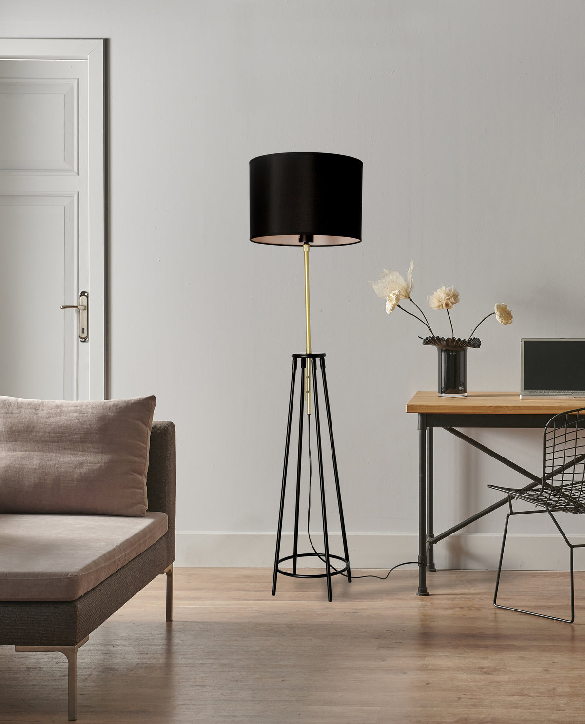 Lampadaire noir et doré en situation dans un salon, près d'un canapé et d'un bureau.