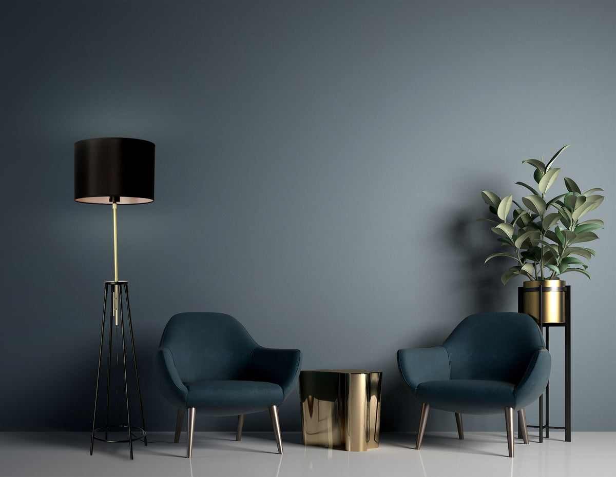 Mise en ambiance sombre avec lampadaire doré, fauteuils bleus et table dorée.