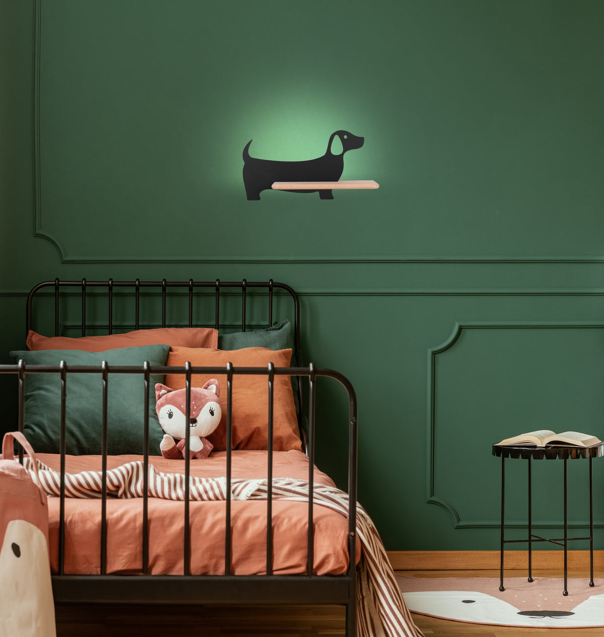 Luminaire chien noir installé au-dessus d'un lit d'enfant, mur vert bouteille.