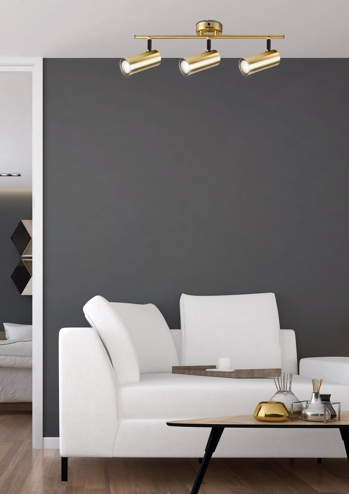 Plafonnier doré installé au plafond d'un salon moderne, canapé blanc et mur gris.