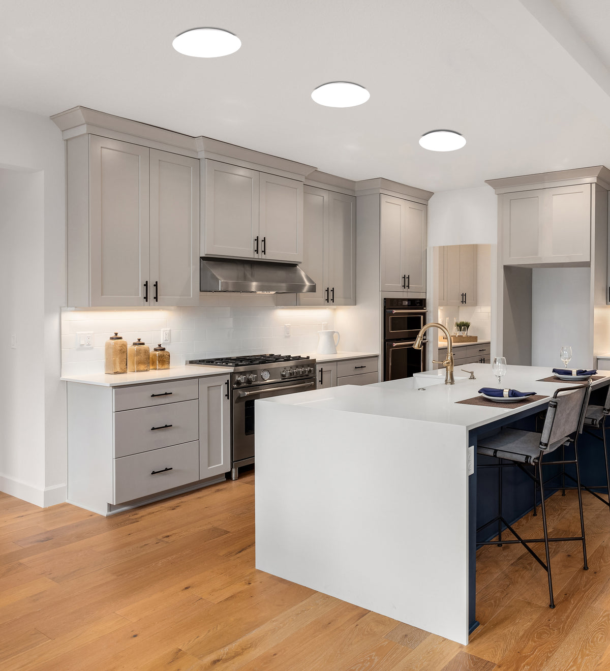 Vue en plafond de trois luminaires ronds allumés dans une cuisine grise