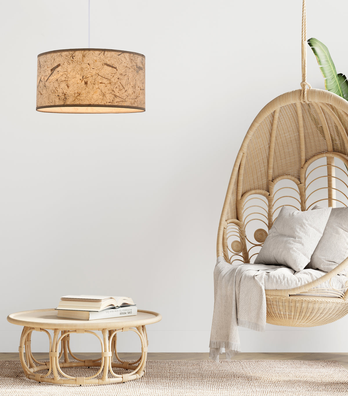 Mise en ambiance intérieure avec suspension beige au-dessus d'un fauteuil suspendu en rotin.