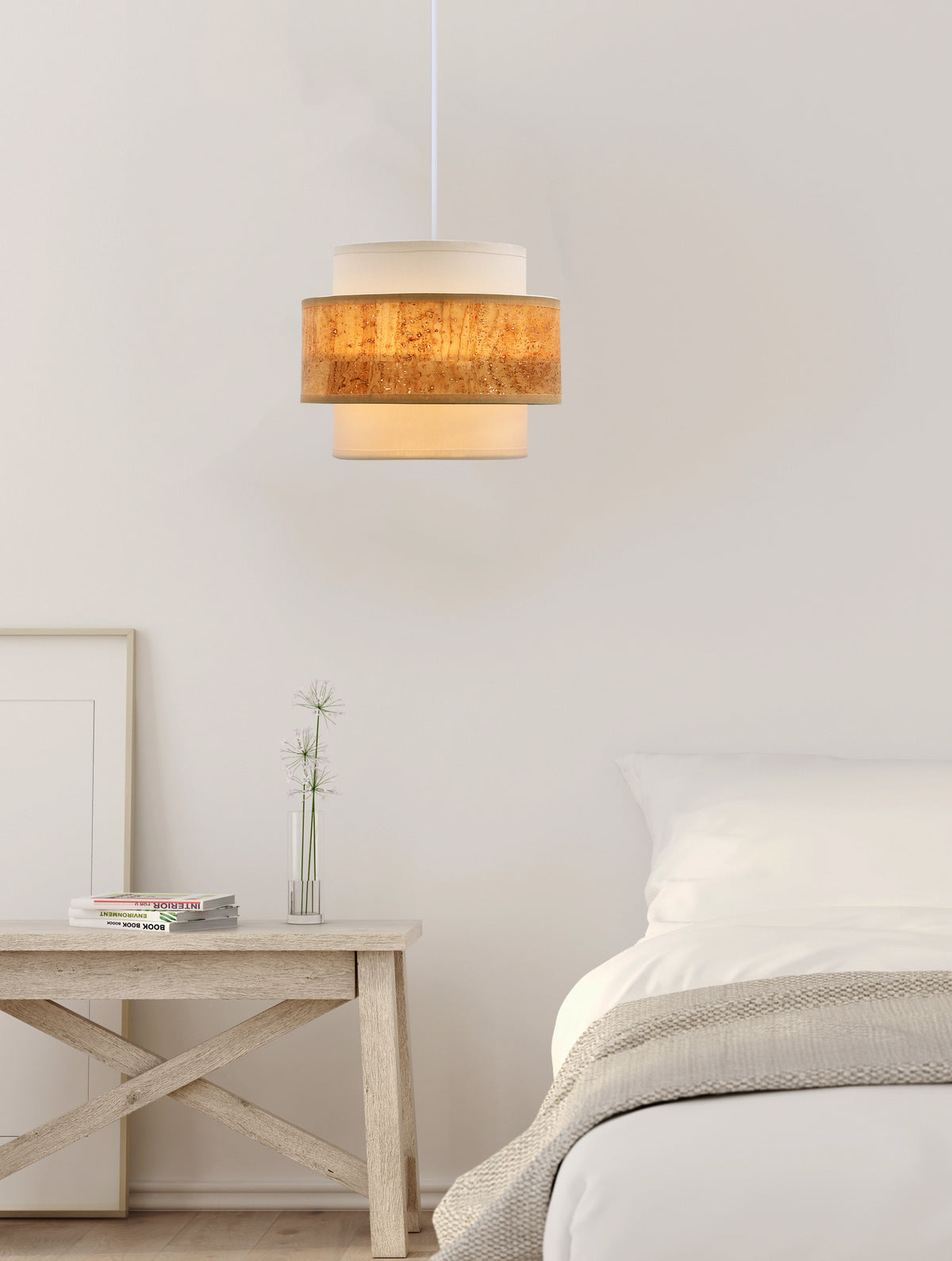 Suspension allumée dans une chambre claire, au-dessus d'une table de chevet en bois.