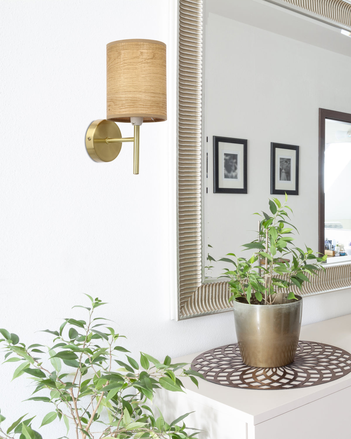 Applique en laiton et abat-jour tissu dans une entrée, devant un miroir et une plante verte