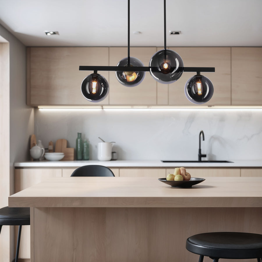 Suspension allumée au-dessus d'un îlot de cuisine en bois clair, avec tabourets noirs.