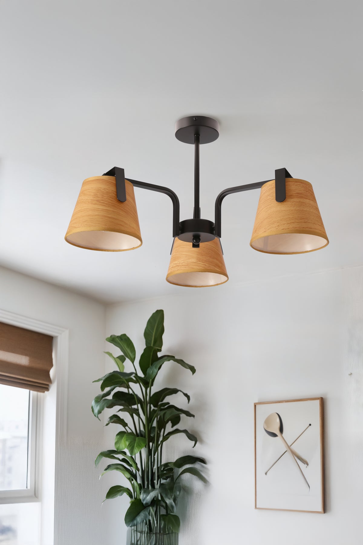 Plafonnier allumé au plafond dans un salon avec plante verte et cadre