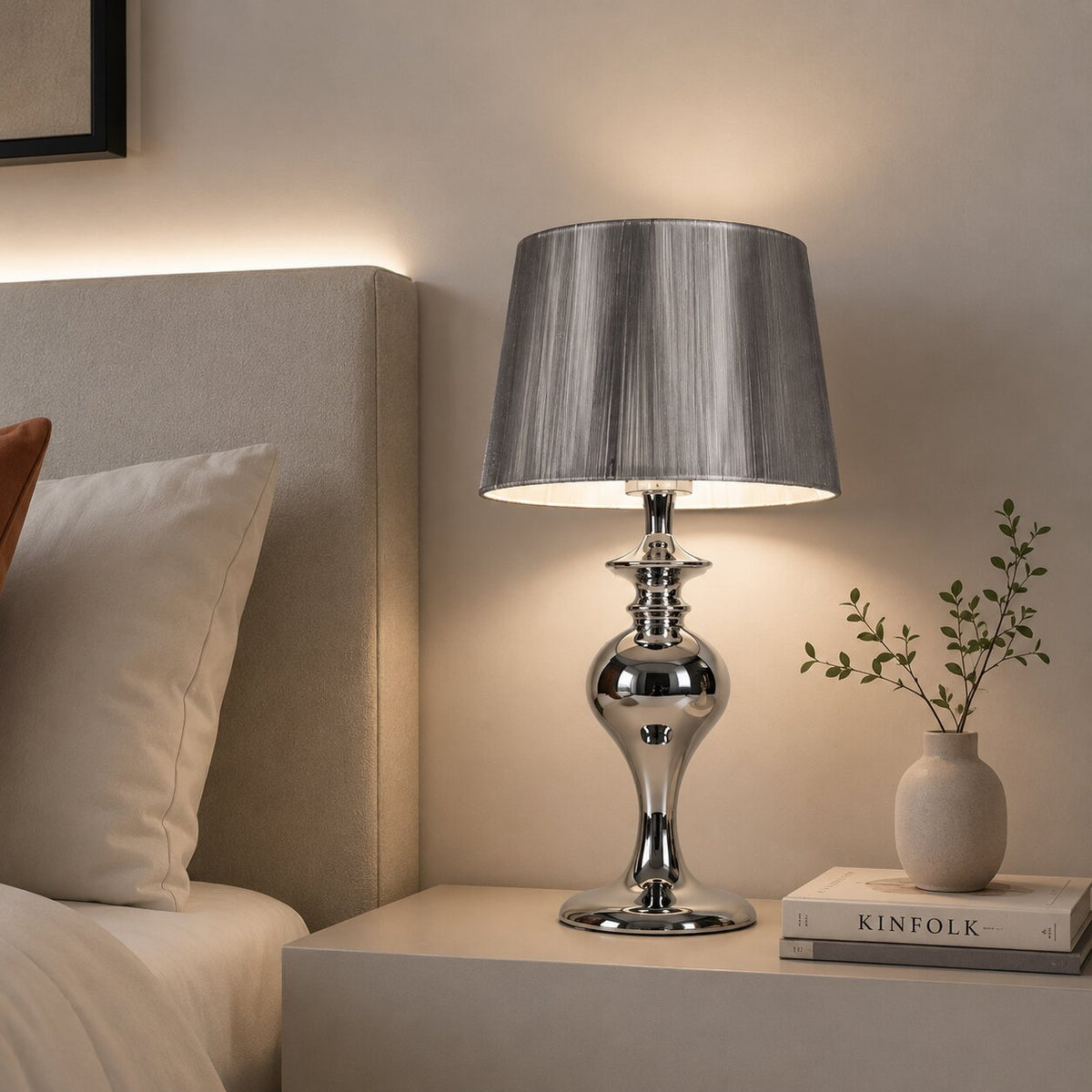 Mise en ambiance chaleureuse de la lampe allumée sur une table de nuit.