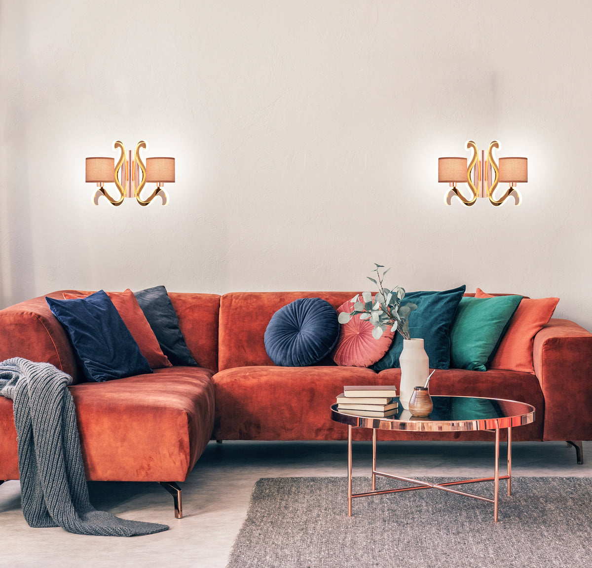 Ambiance de salon moderne avec deux luminaires muraux cuivrés au-dessus d'un canapé en velours.