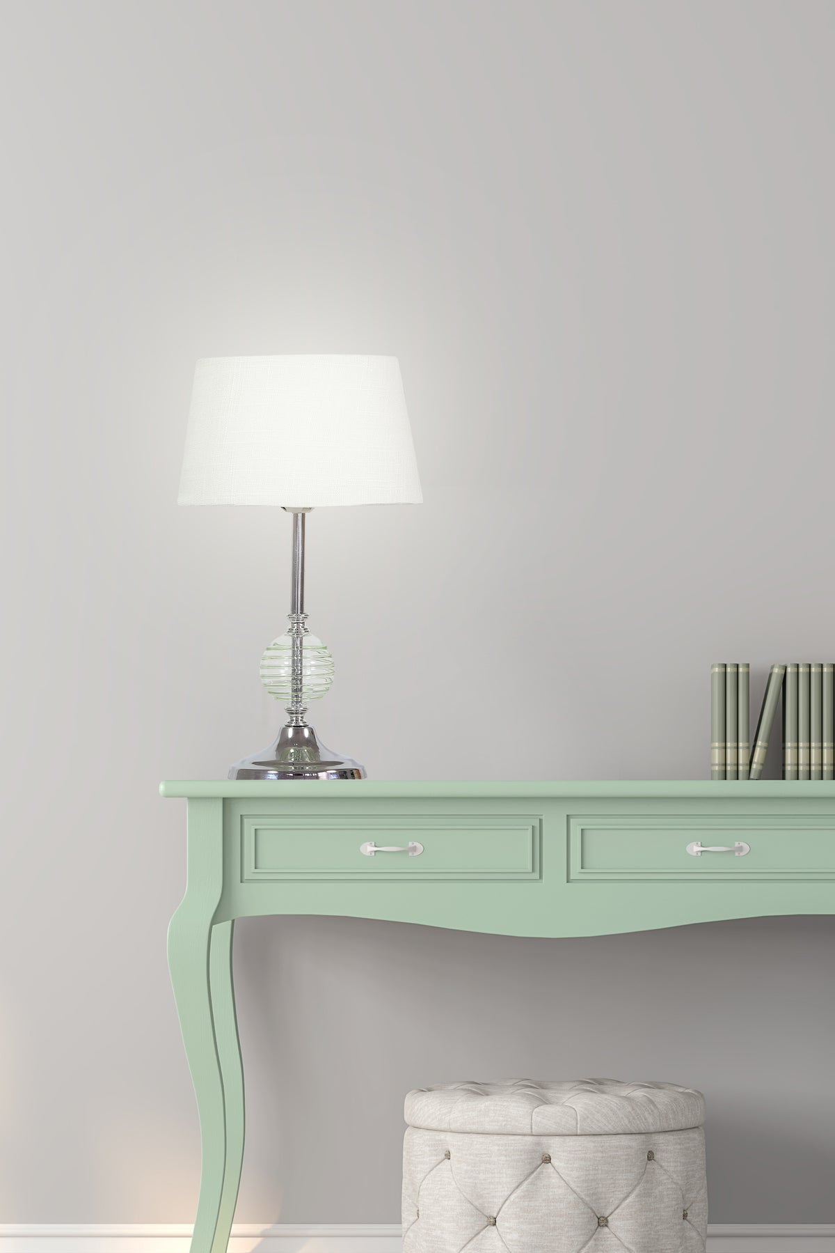Mise en ambiance sur un bureau vert avec livres et pouf, lampe allumée