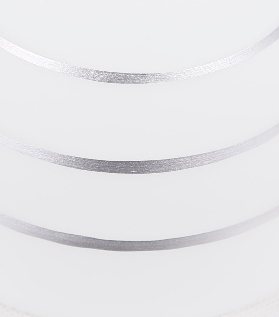 Détail de l'abat-jour en verre blanc strié de lignes horizontales argentées.