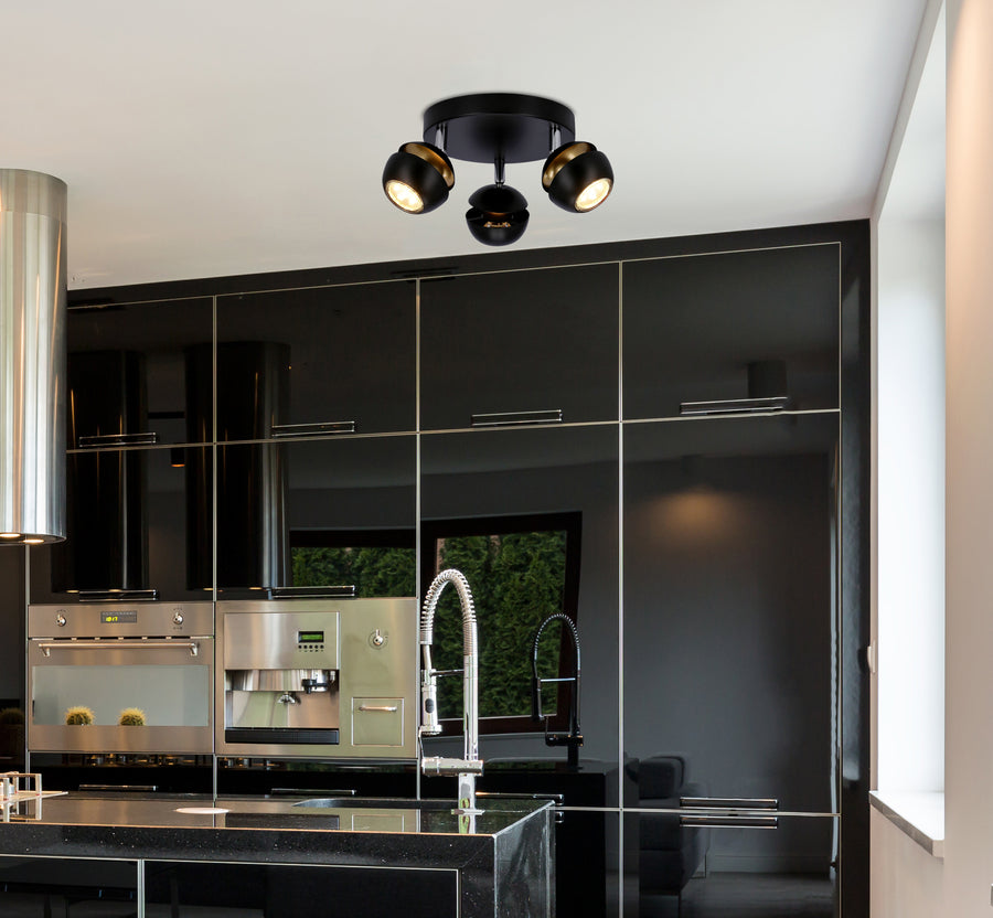 Plafonnier noir installé au plafond dans une cuisine moderne aux façades laquées et équipements inox