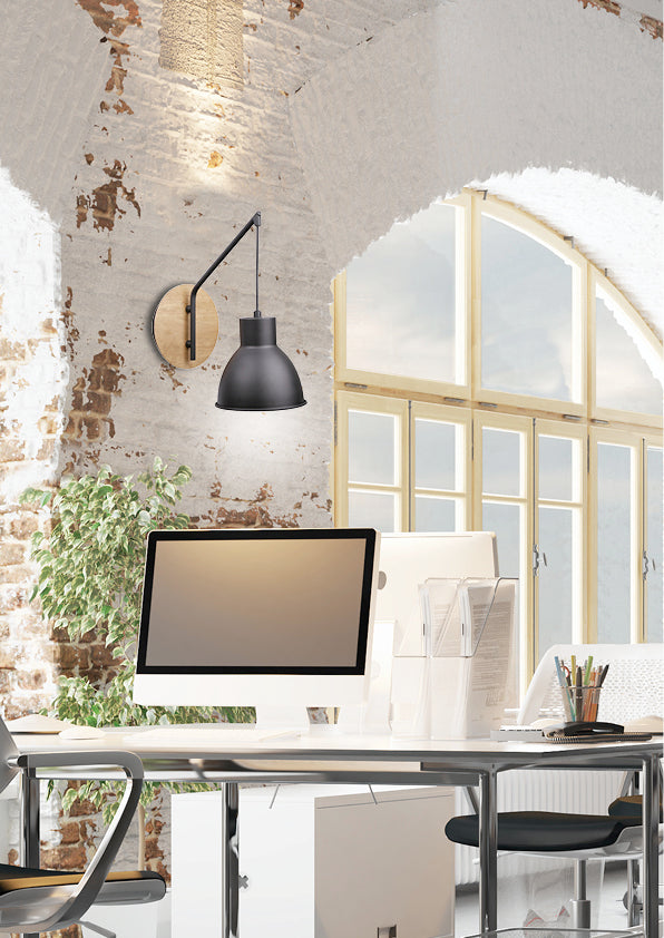Mise en ambiance dans un bureau loft, applique allumée sur mur de briques blanches.