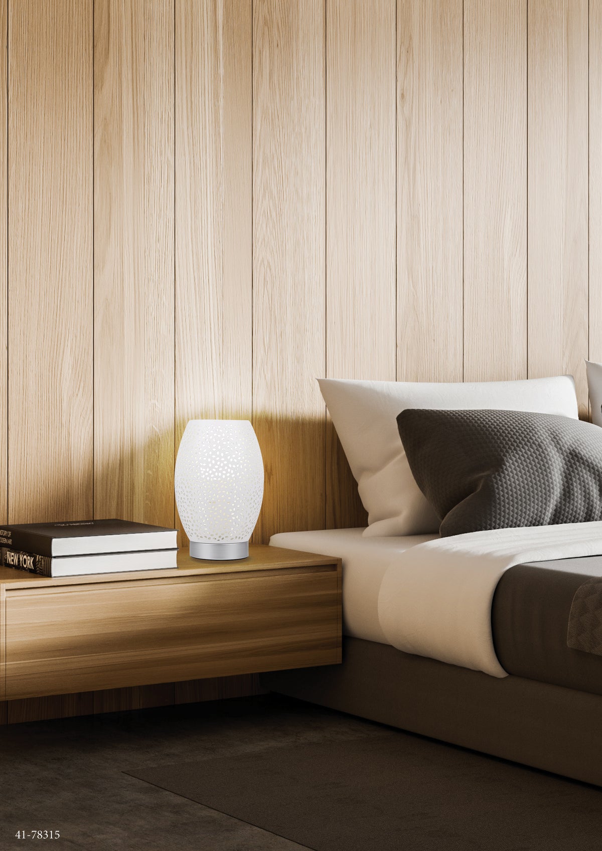 Mise en ambiance chambre, lampe blanche allumée sur chevet en bois, lit et livres.