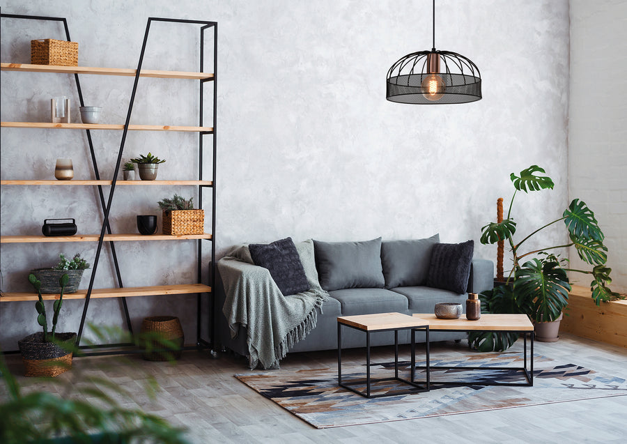 Mise en ambiance salon moderne avec canapé gris, étagère bois et suspension allumée.