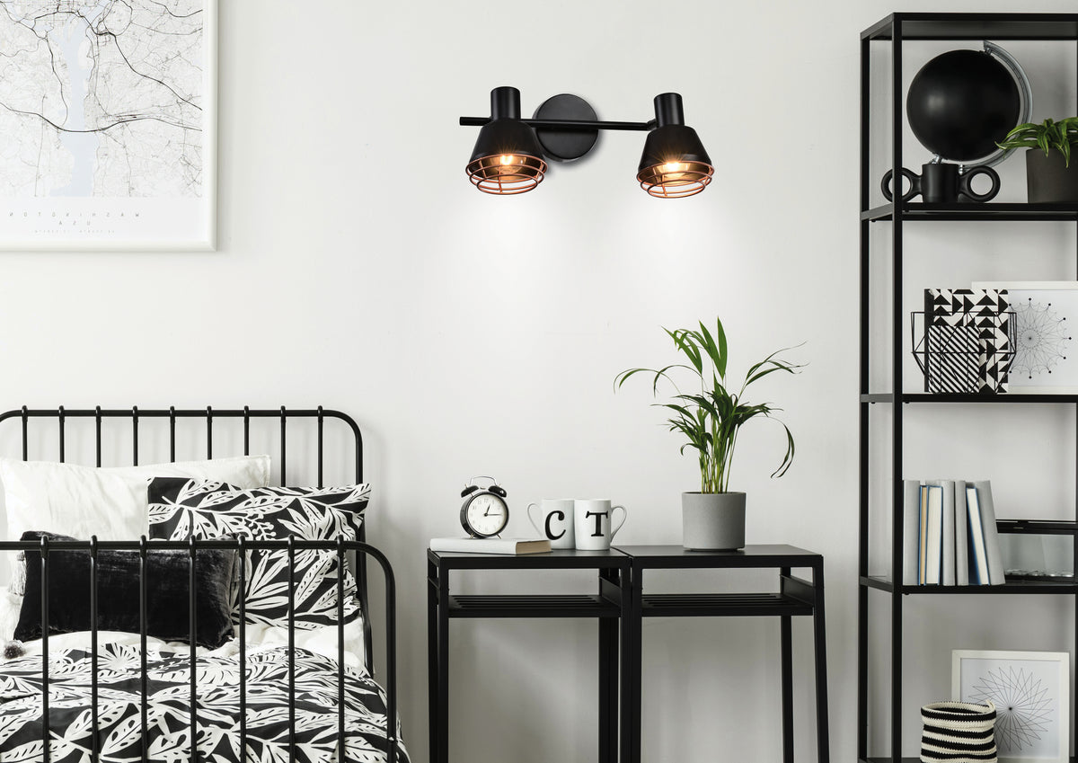 Luminaire mural allumé au-dessus d'une table de chevet dans une chambre.