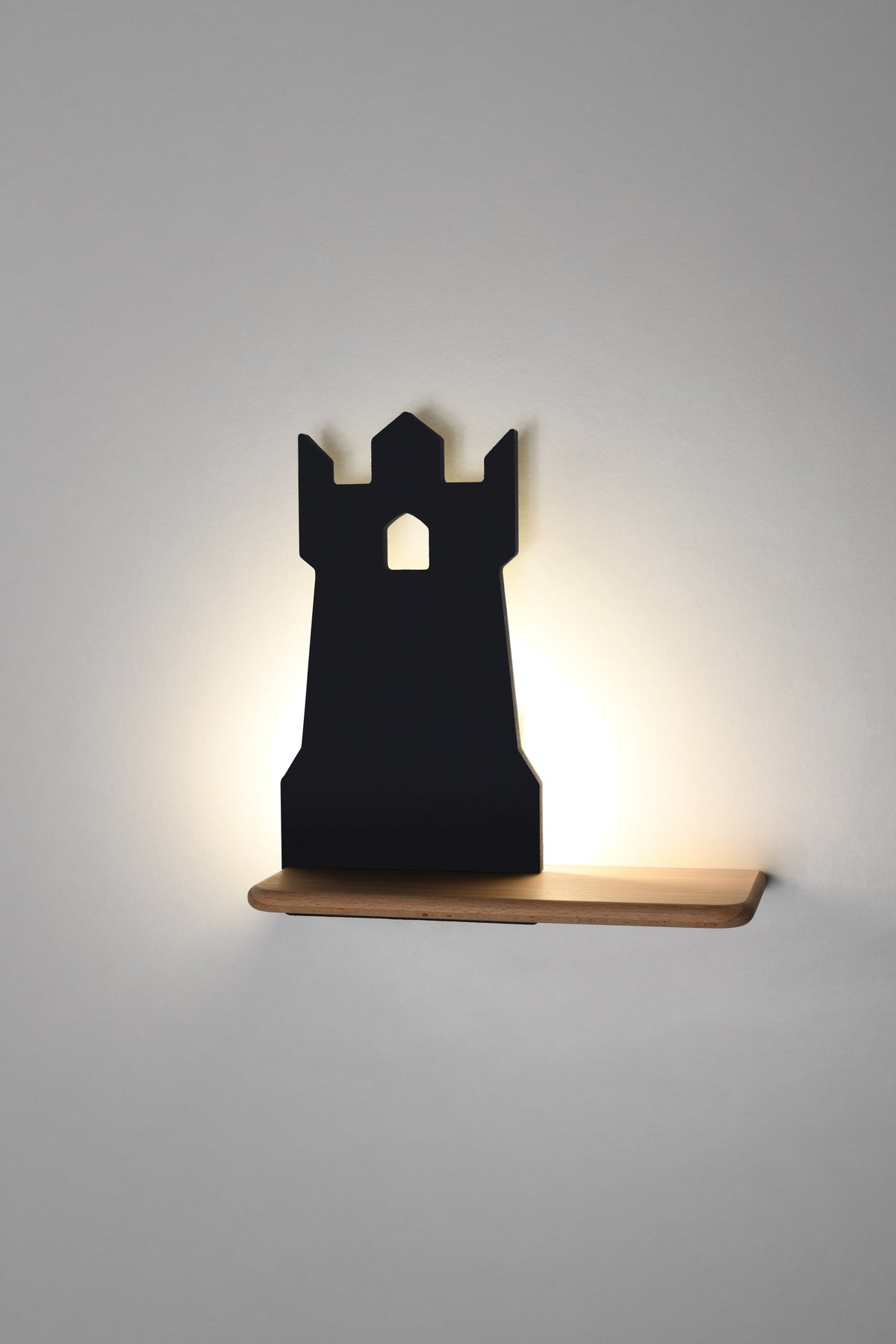Applique noire allumée sur mur clair, lumière chaude diffusée derrière la silhouette
