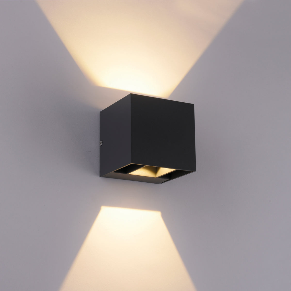 Applique allumée sur mur gris, deux faisceaux lumineux haut et bas