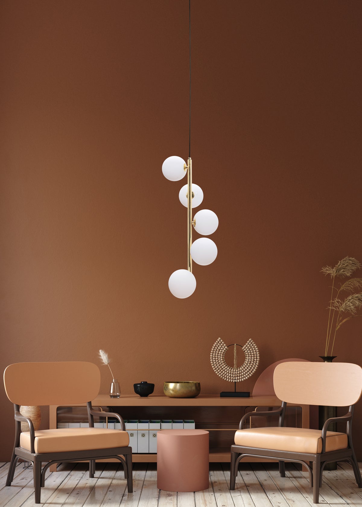 Vue rapprochée de la suspension dorée devant un mur brun et un mobilier design.