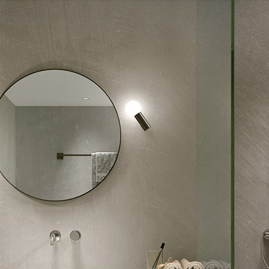 Gros plan de l'applique murale allumée à côté du miroir dans la salle de bain
