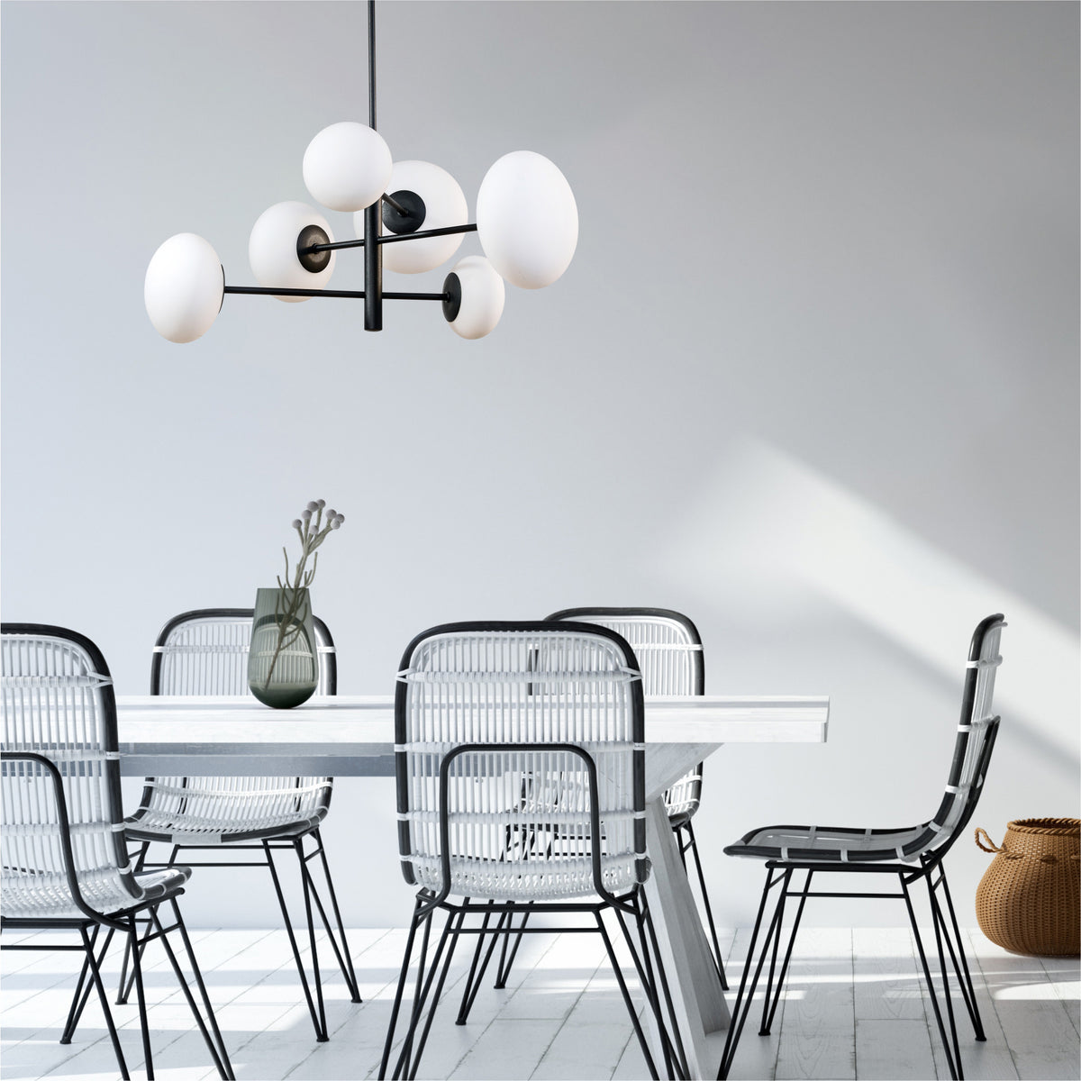 Suspension noire suspendue au-dessus d'une table blanche avec chaises en rotin