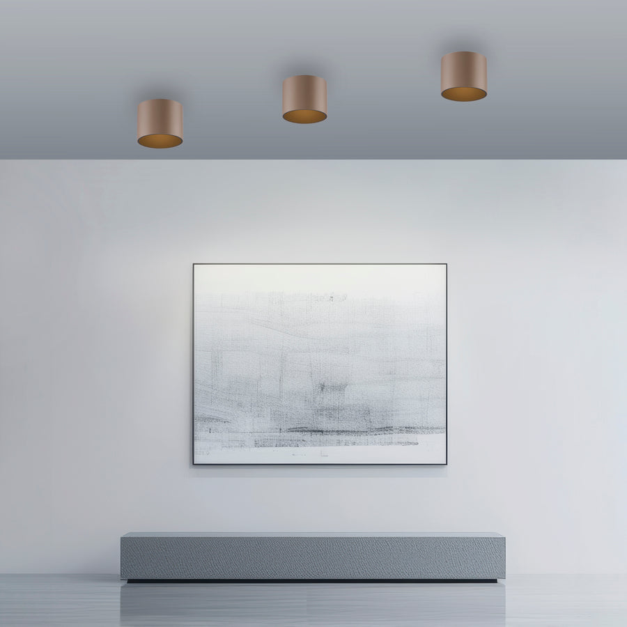 Trois plafonniers alignés au plafond d'un intérieur gris très minimaliste