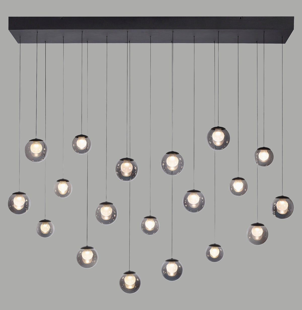 Suspension noire à multiples globes de verre fumé allumés sur fond gris.