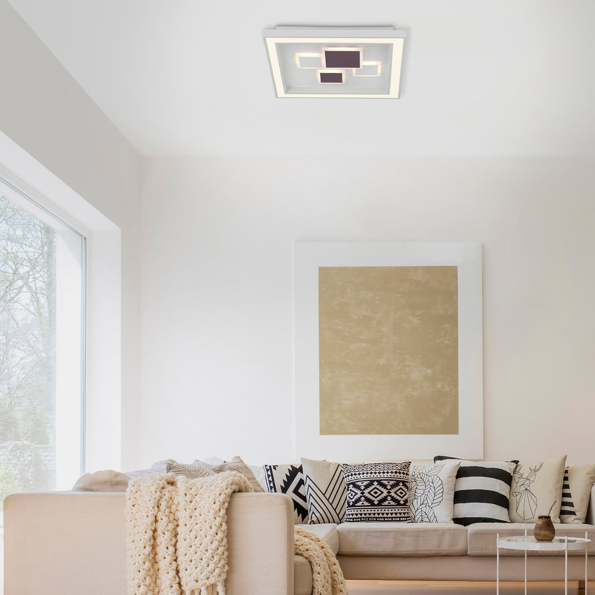 Plafonnier blanc installé au plafond dans un salon moderne avec canapé et coussins décoratifs.