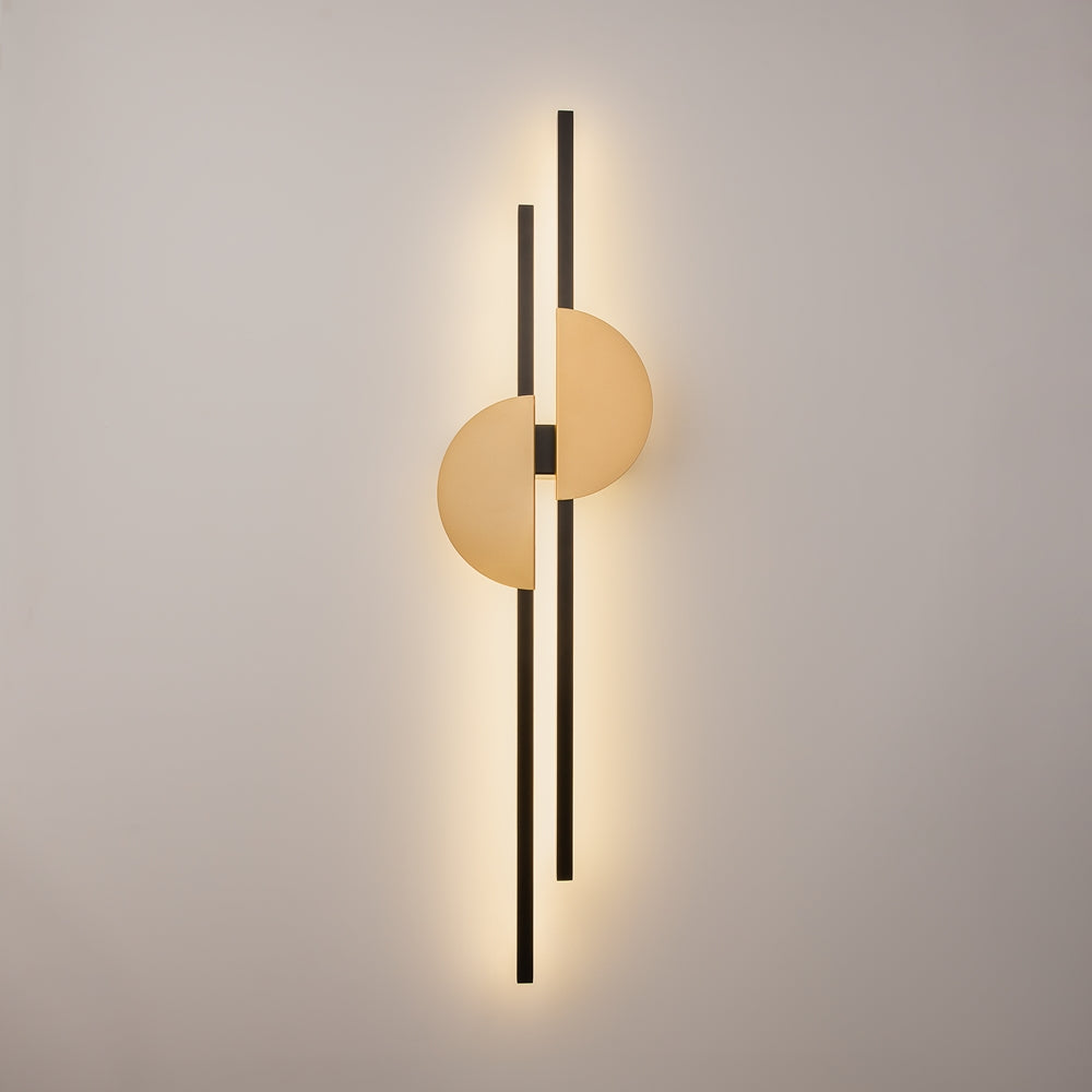 Vue de face fixée au mur, halo lumineux diffus autour du luminaire noir et doré