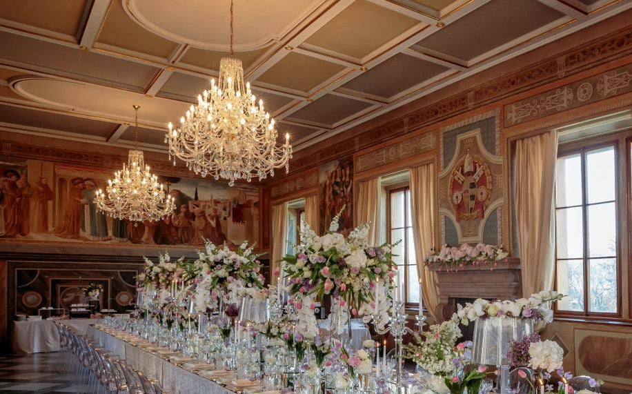 Mise en ambiance du lustre suspendu au-dessus d'une table de banquet fleurie.