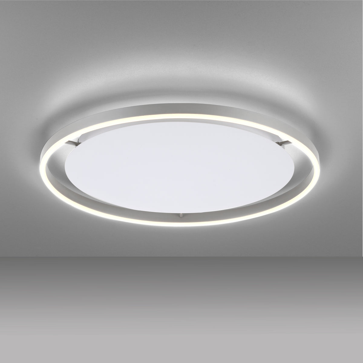 Vue de dessous du plafonnier allumé, montrant l'anneau LED et le diffuseur blanc.