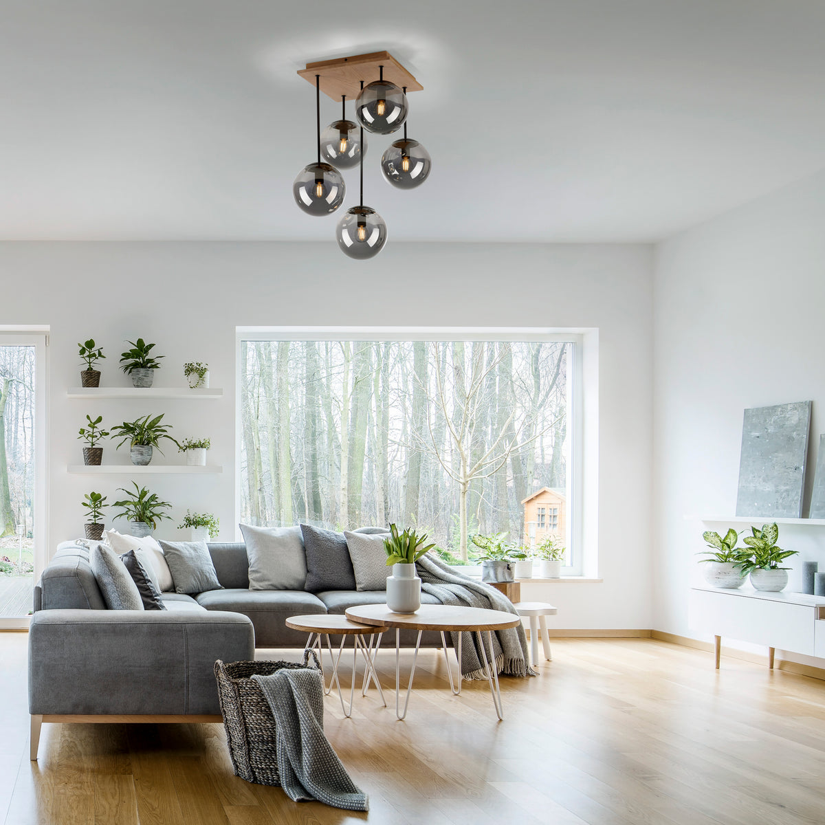 Mise en ambiance dans un salon moderne, plafonnier suspendu au-dessus d'un canapé gris.