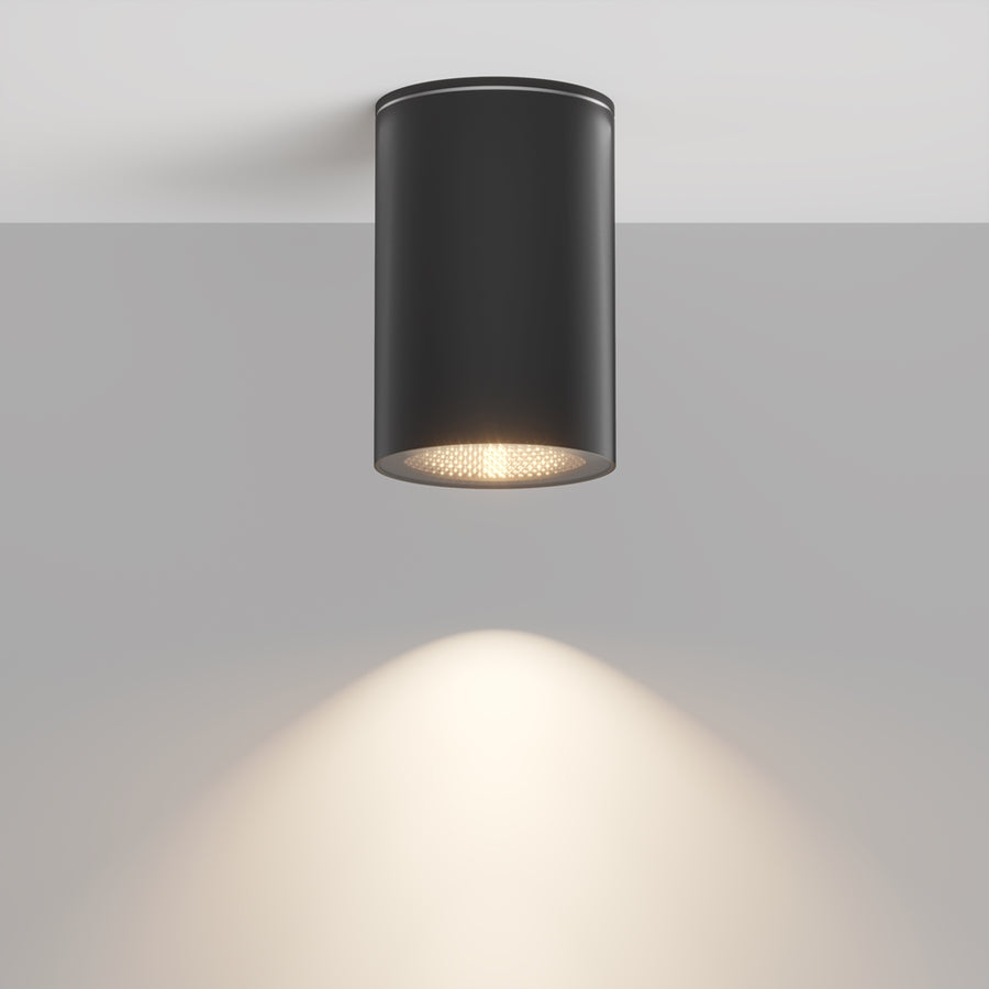 Luminaire cylindrique noir fixé au plafond, halo lumineux projeté vers le bas