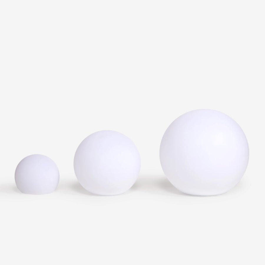 Trois globes lumineux blancs de tailles différentes alignés pour comparer les dimensions