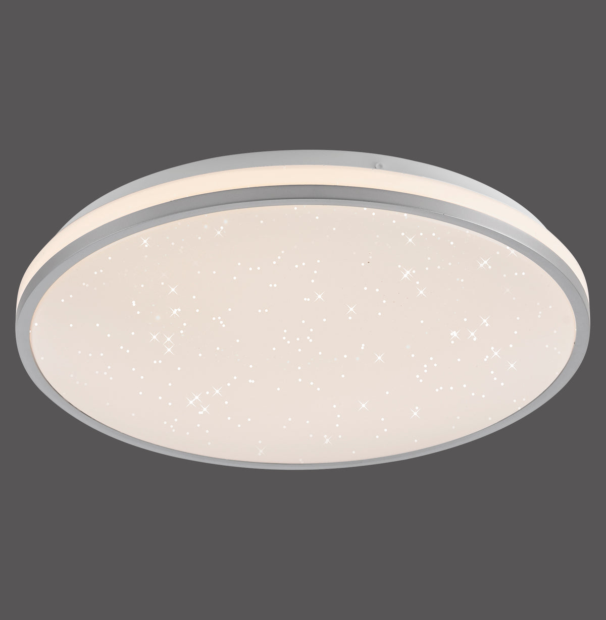 Plafonnier rond argenté allumé, diffuseur blanc avec motif ciel étoilé et liseré gris.