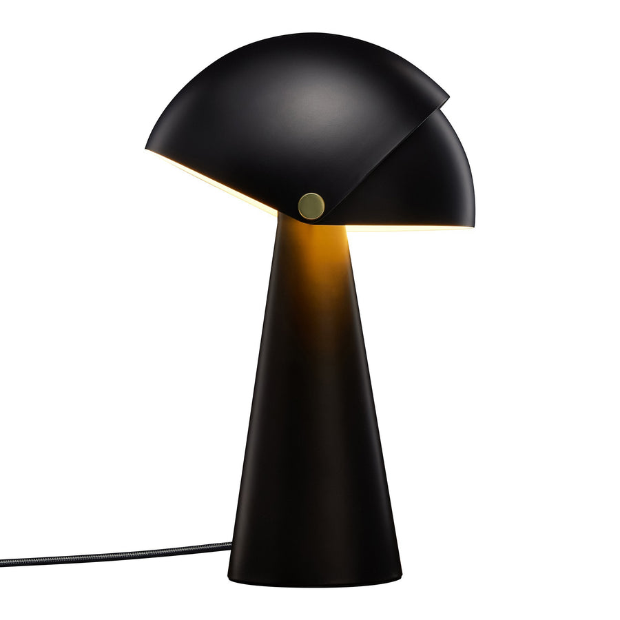Lampe allumée, abat-jour noir diffusant une lumière chaude sur le pied conique.