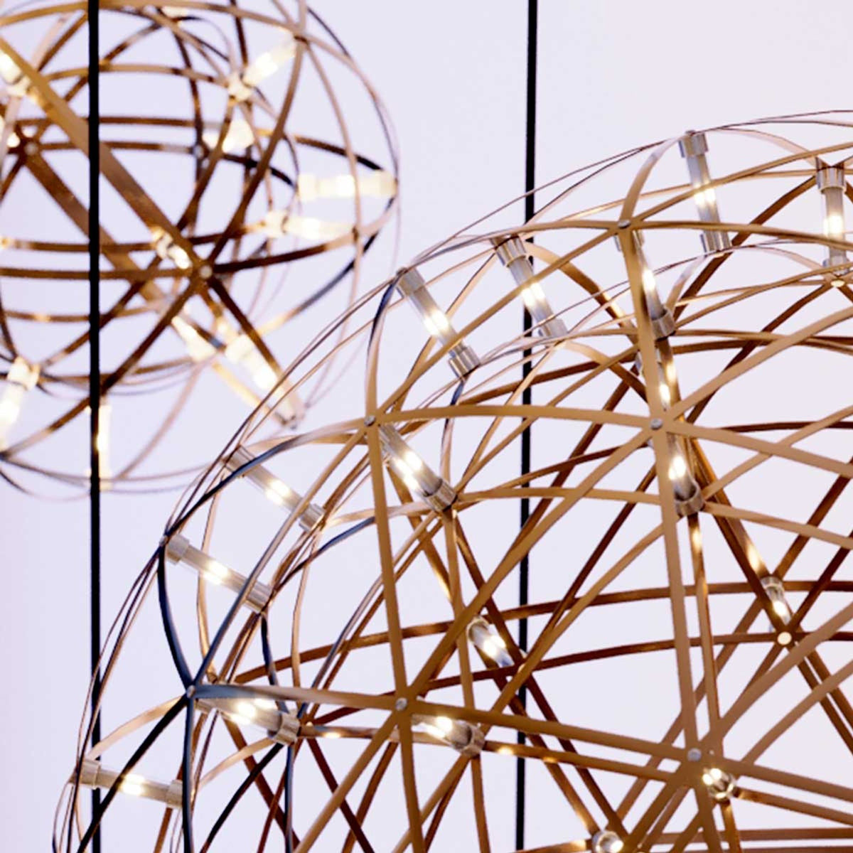 Gros plan sur la structure métallique dorée et les LED des suspensions boules.